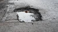 Deep road pothole filled with rainwater.