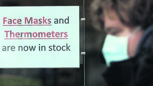<p class="contextmenu internal_Caption">A man wearing a face mask walks past a pharmacy in Dublin during the early stages of the covid pandemic in 2020</p>