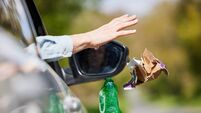 Close Up Of Driver In Car Dropping Trash Out Of Window On Country Road