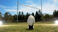 Rugby Ball in front of goal posts.