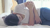 Woman lying on bed, suffering from strong stomach pain, endometriosis,  menstruation.