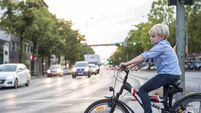 Boy with bicycle is waiting at the traffic light of a big road