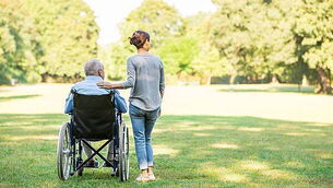 Senior man sitting on a wheelchair with caregiver
