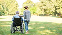 Senior man sitting on a wheelchair with caregiver