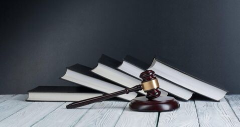 Law concept - Open law book with a wooden judges gavel on table in a courtroom or law enforcement office isolated on white backg