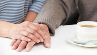 Close Up Of Woman Sharing Cup Of Tea With Elderly Parent