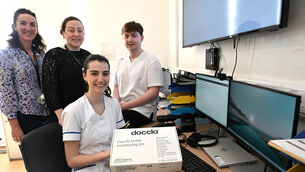 <p>At the virtual monitoring hub in the hospital ward are (rear) Anna Higgins, service improvement lead, Alison Lane, assistant director of nursing, and Aidan Ryan, staff nurse with (seated ) staff nurse Jennifer O’Connell with the box containing the Doccla virtual care home monitoring kit. Picture: Larry Cummins.</p>