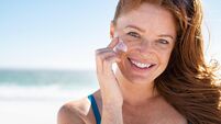 Mature woman applying sunscreen on face
