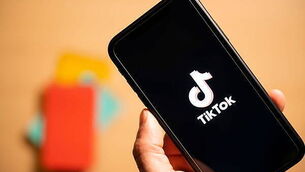 Rome, Italy, 24 January 2021. Overhead shot of a human hand holding a smartphone with the TikTok logo.