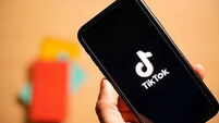 Rome, Italy, 24 January 2021. Overhead shot of a human hand holding a smartphone with the TikTok logo.