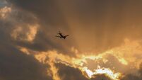 Airplane flying through dramatic sunset clouds with sun rays breaking through