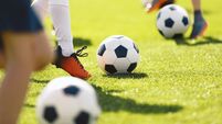 Boys kick football balls. Children attending outdoor soccer class. School children running and kicking balls on summer training
