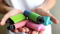 Many colorful electronic cigarettes in the hands of a teenager. Vaping with nicotine. Danger for teenagers.