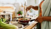 Woman preparing quinoa vegetable mix cooked in a frying pan
