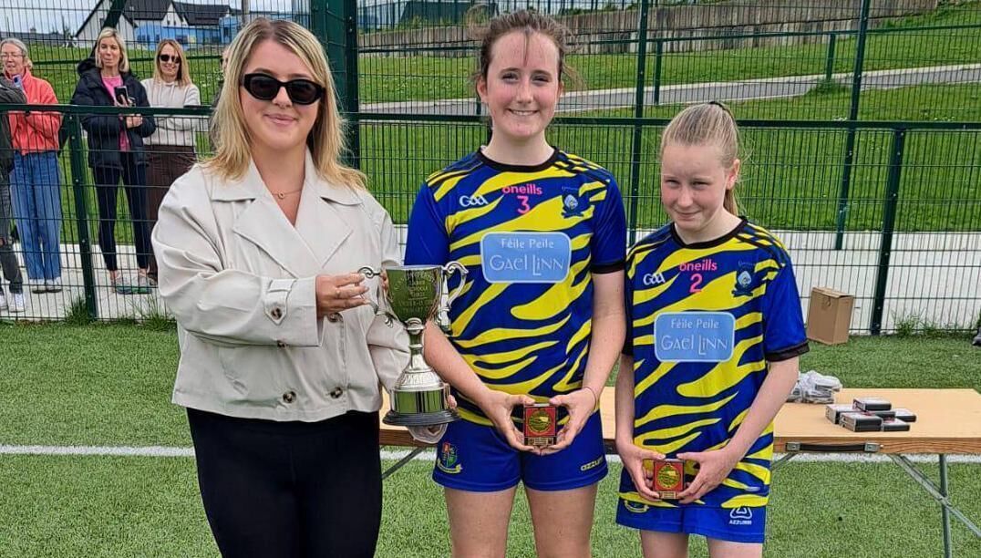 Gaelscoil Carrigaline captains Eirinn Cambridge and Hannah Bray Duncliffe presented with the John Kennedy Memorial Cup by his daughter Grace Kennedy, at the Cork Primary Schools 11-a-side Soccer competition. Gaelscoil Carrigaline captains Eirinn Cambridge and Hannah Bray Duncliffe presented with the John Kennedy Memorial Cup by his daughter Grace Kennedy, at the Cork Primary Schools 11-a-side Soccer competition.