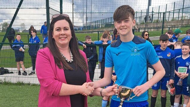 <p>Holy Well Carrigaline captain Eoin O’Leary being presented with the Derek Collins Perpetual Cup by Elaine Spillane, his niece, at the Cork Primary Schools 11-a-side Soccer competition.</p>
