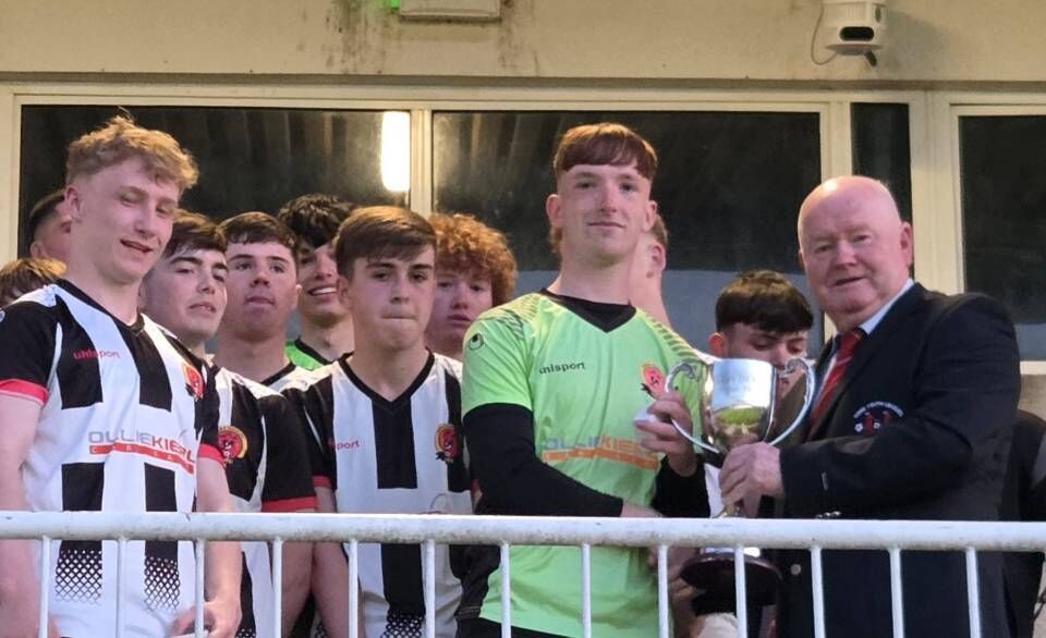 Denis Crowley from the Cork Youth League presenting the U17 Teddy Healy Cup to Midleton captain Jack Mills at Munster FA Turner’s Cross.