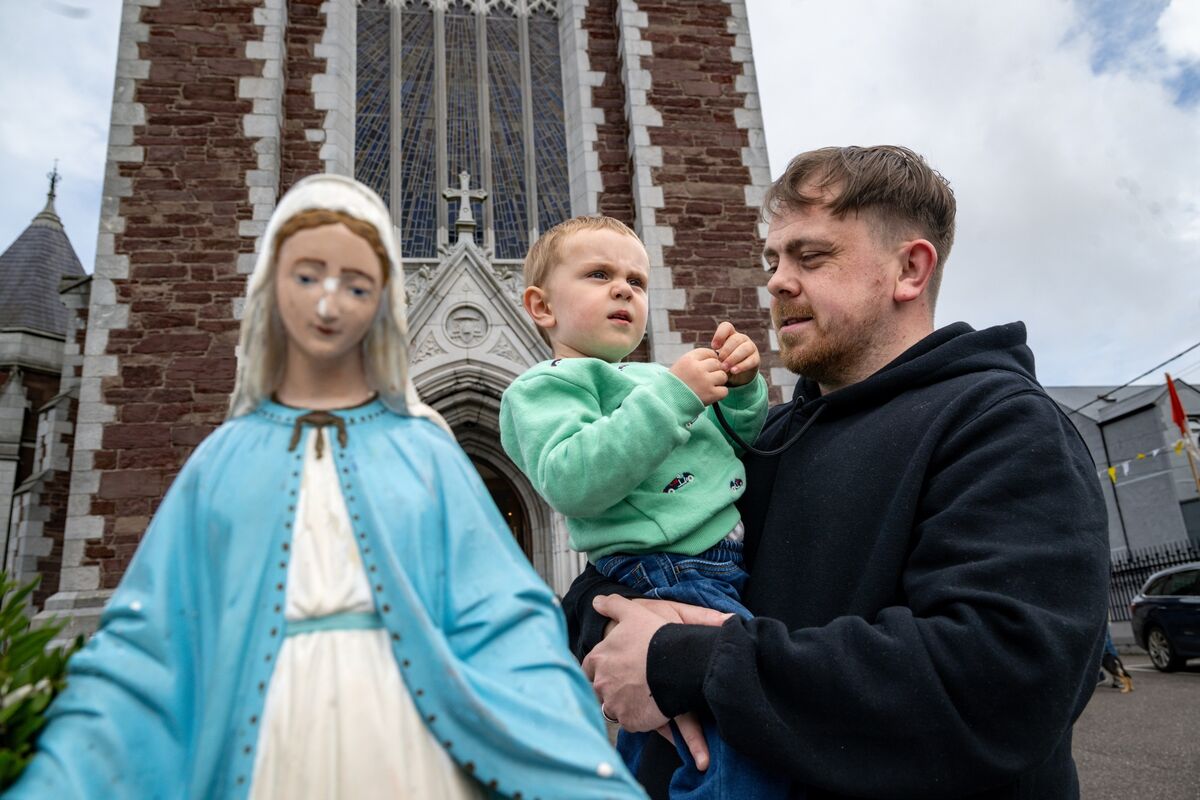 Craig Clinton and his son Kaiden share a moment beside the statue of the Virgin Mary on Cathedral Avenue, where Craig hopes the family tradition begun by his grandmother Kathleen O’Sullivan will continue through future generations. 