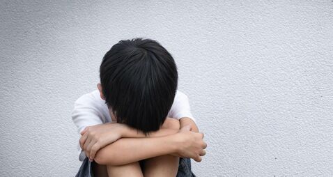 2CGEEK2 A boy sitting alone with sad feeling. Asian little child covered his face with his hands in fear. Domestic Family violence conc