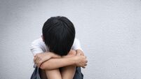 A boy sitting alone with sad feeling. Asian little child covered his face with his hands in fear.  Domestic Family violence conc