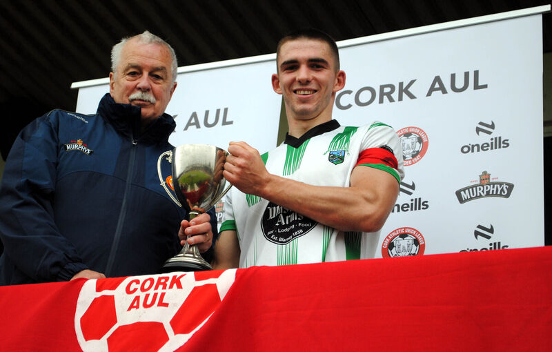 John Coughlan (Cork AUL) presents the County Cup to Waterloo's Jack Homan following his side's 4-2 victory over Belmount Celtic. John Coughlan (Cork AUL) presents the County Cup to Waterloo's Jack Homan following his side's 4-2 victory over Belmount Celtic.