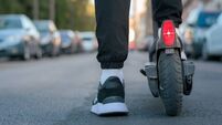 Close-up of a man riding an electric scooter on a street. Ground view