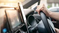 Male driver hand holding on steering wheel using smartphone for GPS navigation. Mobile phone mounting with magnet on the car con