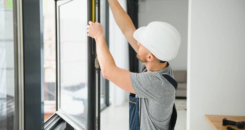 handsome young man installing bay window in new house construction site