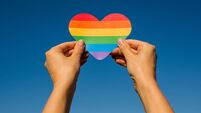 Woman holds in hands a heart in the colors of the rainbow. Young beautiful girl. LGBT history month. Pride Month. Lesbian Gay Bi