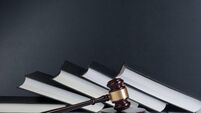 Law concept - Open law book with a wooden judges gavel on table in a courtroom or law enforcement office isolated on white backg