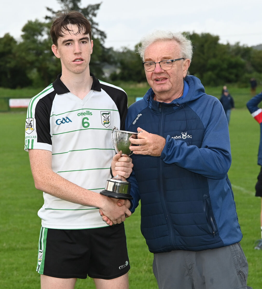Aidan Lutrell, Rebel Óg presents the trophy to Douglas captain Emmett Cronin after defeating Nemo Rangers in the Rebel Óg under 16 Premier 1 football league final at Shanbally. 