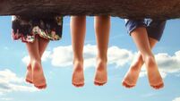 Children sitting in a tree dangling their feet