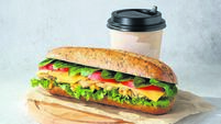 Sandwich with lettuce, tomatoes, chicken, cheese, sorrel and a cup of coffee (tea) on wooden cutting board.