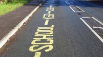 Yellow warning sign, School Keep Clear, painted tarmac road, no-parking