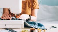A woman tailor works at sewing machine sews reuses fabric from old denim clothes