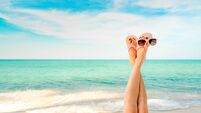 Upside woman feet and red pedicure wear pink sandals, sunglasses at seaside. Funny and happy fashion young woman relax on vacati