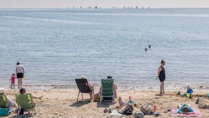<p>Crosshaven, - Visitors to the beach enjoy the hot weather as yachts race outside the harbour at Fountainstown, Co. Cork. - Picture: David Creedon</p>