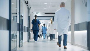 Hospital Hallway with Doctors, Nurses and Specialists in Hospital. Female and Male Physicians, Surgeons, Healthcare Officials Wa