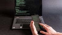 Person with computer and mobile phone hacking with the PEGASUS program.