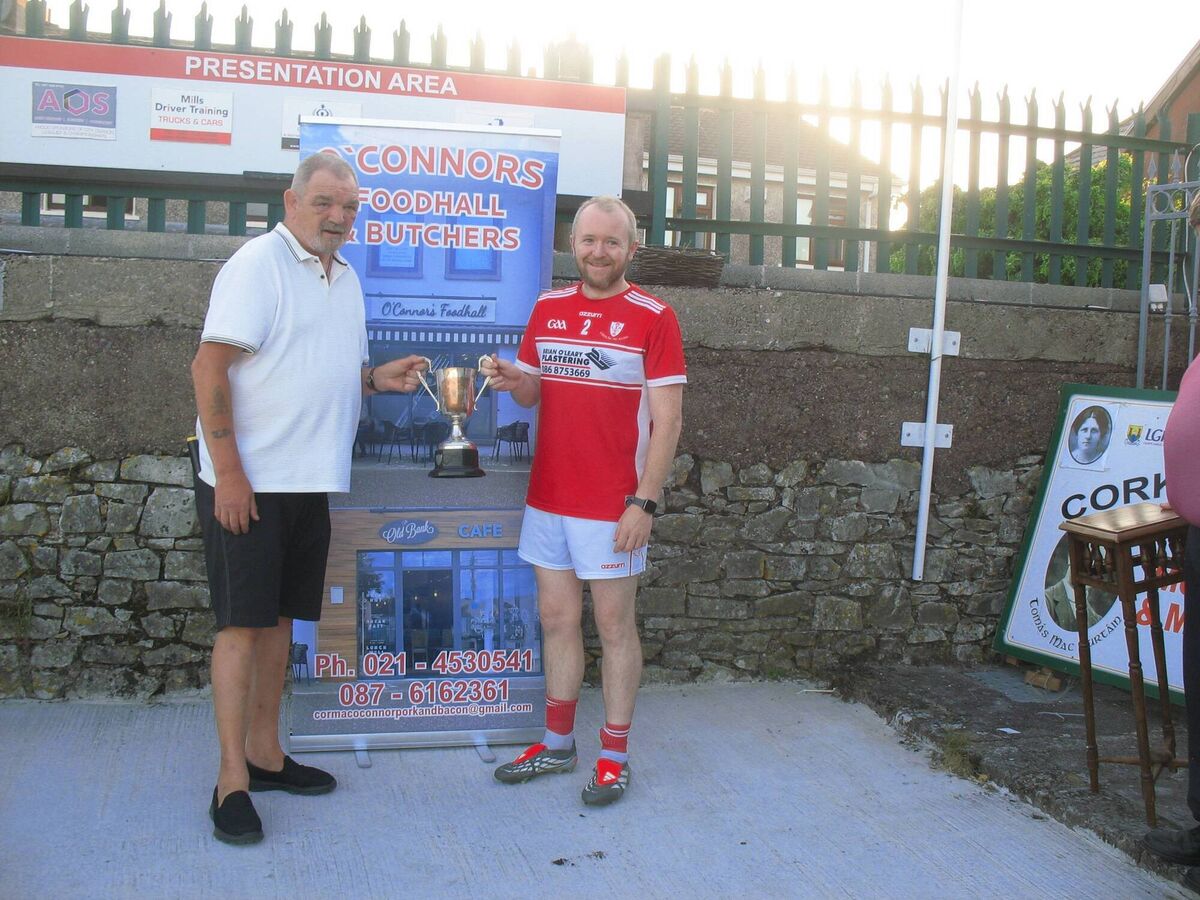 Seandún Chairman Mick Buckley presents the Cormac O'Connor Butchers &amp; Foodhall Flor McCarthy Cup to Lough Rovers winning captain Niall O'Sullivan