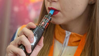 A young woman smokes electronic cigarettes