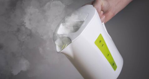White Boiling Kettle in hand on dark background