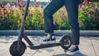 girl is taking her black and red electric scooter denim style flowers behind her outside