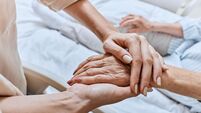 Relative holding trembling hand of senior woman with Parkinson's disease lying in hospital bed at medical ward. Diagnosis and tr