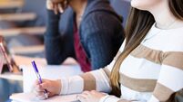Unrecognizable female college student takes notes in class