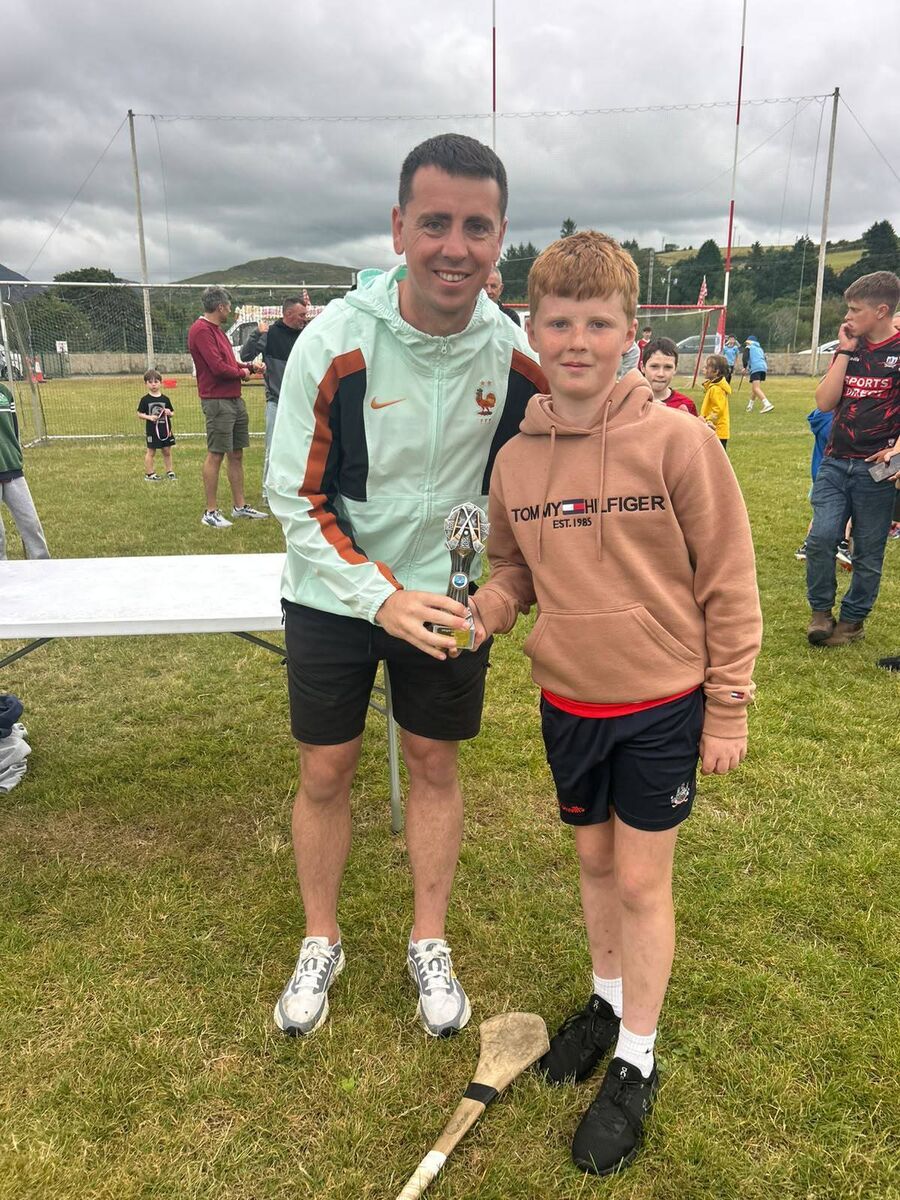 Former Dublin footballer Cormac Costello, the winner of the Adrigole GAA Long Puc competition, presenting the winner of the juvenile section, Evan Gleeson, with his prize.