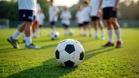 Youth soccer players practice on field. Stand in line, ready for training. Focus on black, white soccer ball. Scene shows sports