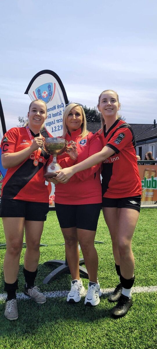 Ringmahon co-captains Kayleigh Still and Aibhe O'Donovan receive the cup from the CWSSL's Ciara Horgan