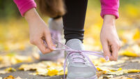 Hands tying trainers shoelaces on the autumn pave