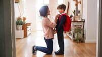 Single Mother At Home Getting Son Wearing Uniform Ready For First Day Of School